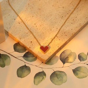 Detail of red heart pendant with gold beaded edges on a minimalist necklace