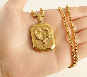 Detail of 18K gold stainless steel square dragon pendant held in hand for scale