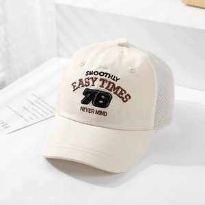 Detail view of cream mesh trucker hat with breathable fabric and brown letter embroidery