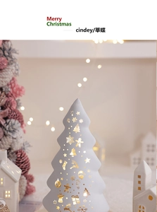 Detail of white ceramic Christmas tree with warm LED light and star cutout patterns