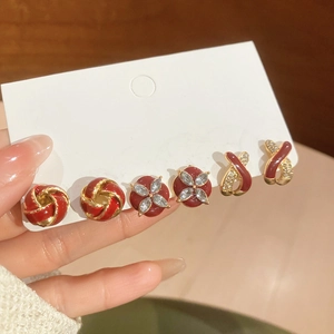 Detail of red enamel gold earrings set featuring flower and knot designs on a card