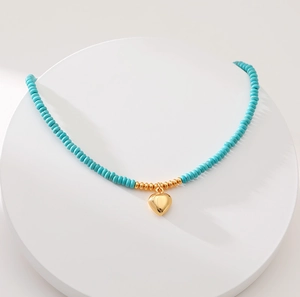 Handmade turquoise beaded necklace featuring a stylish golden heart-shaped pendant
