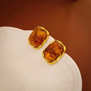 Macro shot of rectangular amber resin earrings with irregular gold plated metal edges