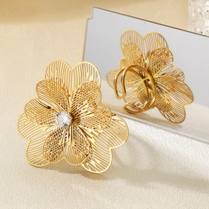 Gros plan de la bague fleur évidée avec zircon blanc sur une texture en tissu doré