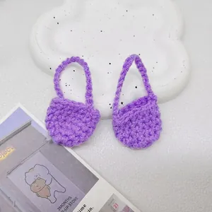 Dettaglio di due mini borse viola fatte a mano all'uncinetto con trama a maglia