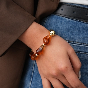 Close-up of amber resin beads and gold metal accents on a stylish beaded bracelet