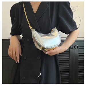 Detail of silver metallic hobo bag with gold letter branding and elegant chain strap