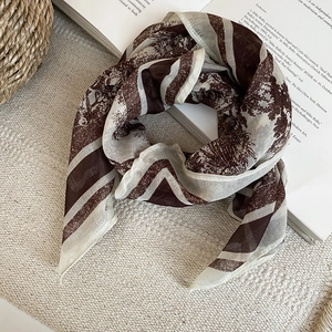 Close-up of vintage printed silk scarf in dark coffee and beige with retro botanic patterns
