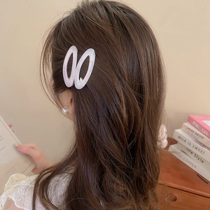 Detail of lavender oval acetate hair clips worn on wavy brown hair in a cozy setting