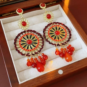 Detail shot of vintage bohemian tassel earrings with red beads in a luxury wooden box