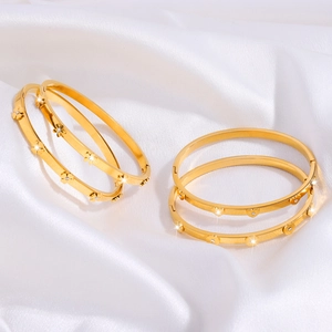 Elegant gold titanium steel bracelets with floral and heart charms on silk background