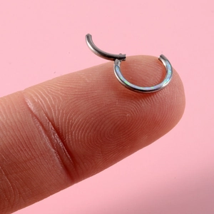 Makroaufnahme von G23 Titan-Hinged-Ring mit blauem Opal-Inlay auf rosa Hintergrund