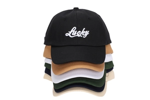 Detail view of cotton baseball caps with Lucky embroidery in multiple color options