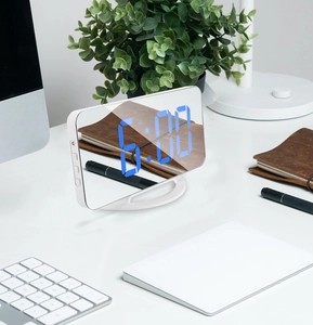 Macro detail of white LED mirror clock on a clean office desk with blue digits