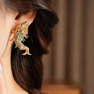 Close-up of vintage fish earrings with blue and purple crystals on a gold base