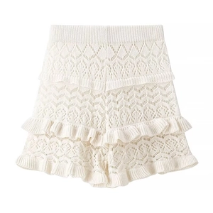 Detail of beige knitted shorts featuring hollow patterns and layered ruffle trim