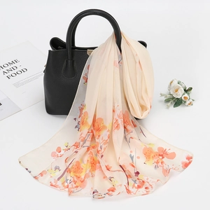 Petit foulard en mousseline fleurie suspendu à un sac à main en cuir noir élégant