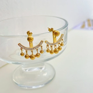 Boucles d'oreilles franges dorées élégantes avec diamants et perles sur un verre