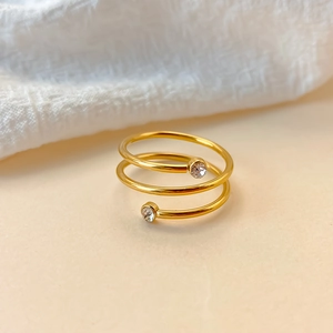 Detailansicht eines goldenen Spiralrings mit zwei funkelnden Zirkonia-Steinen