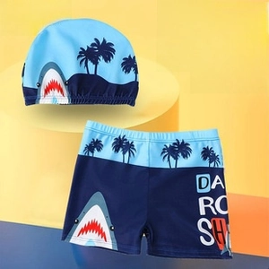 Close-up of kids swim set featuring a blue shark pattern swim cap and boxer trunks