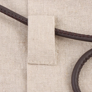 Dettaglio della trama in lino beige e del cordoncino in pelle marrone scuro con cuciture