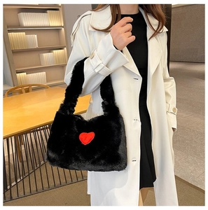 Detail view of black plush shoulder bag featuring a striking red heart pattern and soft texture