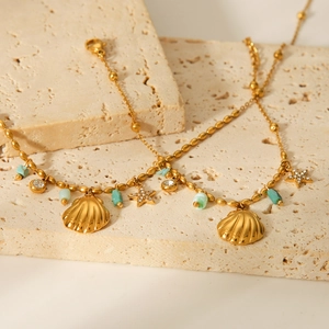 Golden shell and star pendant anklet with turquoise beads on a stone surface