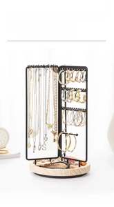 Close-up of rotatable jewelry organizer with black metal hooks and wooden base detail