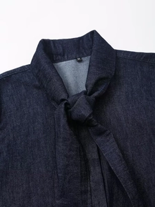 Détail de l'encolure d'une chemise en jean bleu foncé avec un nœud papillon élégant