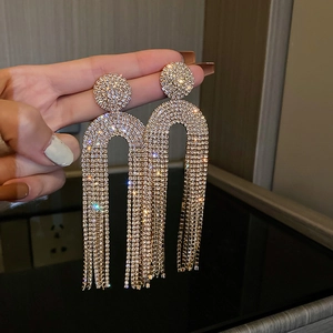 Macro detail of gold U-shaped tassel earrings with pavé white rhinestones for women