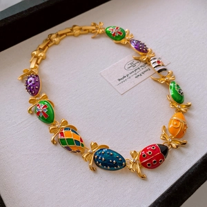 Detail of colorful enamel charms featuring ladybugs and bees on a golden metal necklace