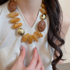 Exaggerated necklace with amber acrylic beads and gold-tone accents worn by model