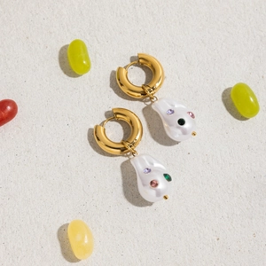 Detail of gold titanium steel earrings with baroque pearls and colorful gemstones