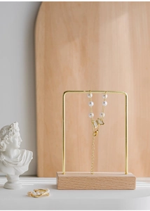 Detailed view of a gold butterfly pendant necklace with pearls on a jewelry stand