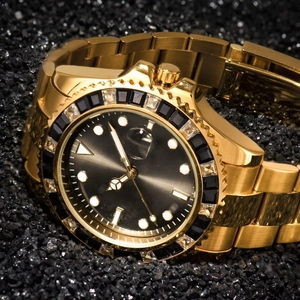 Detail of gold luxury watch with black crystal bezel and date window magnifier