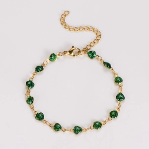 Detailed top view of a gold heart bracelet with green glitter charms and a lobster clasp