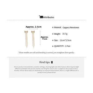 Detail of gold bow earrings with long rhinestone tassels measuring 11cm by 2.5cm
