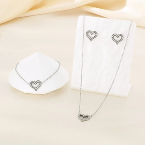 Detailed view of silver heart-shaped jewelry set with micro-pave crystals on fabric