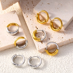 Polished chunky hoop earrings set in gold, silver, and two-tone finishes on beige stone