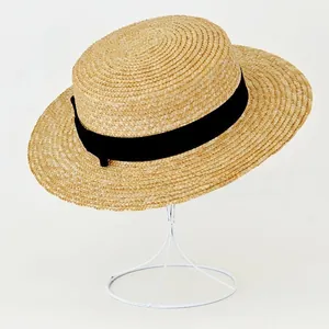 Close-up of a straw boater hat featuring a flat top and a classic black ribbon band