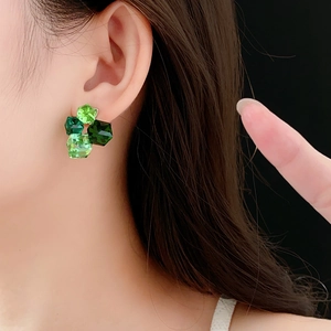 Close-up of geometric green faceted crystal stud earrings showing craftsmanship
