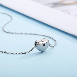 Polished silver heart pendant necklace in stainless steel on a light blue background