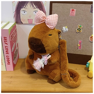 Detailed view of Capybara plush bag with pink bow and rabbit doll on a wooden table