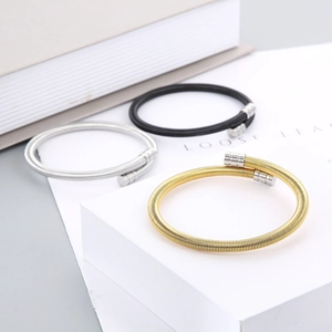 Detailed shot of three woven mesh steel spring bracelets in gold, silver, and black finishes