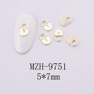 Détails macro des breloques à ongles en alliage doré de 5x7mm sur fond violet texturé