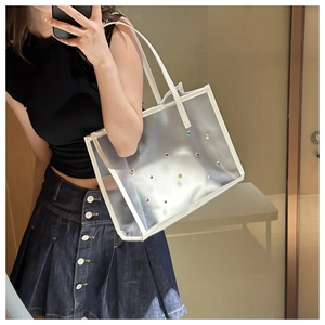 Close-up of clear PVC tote bag with colorful rhinestones shown in a mirror selfie
