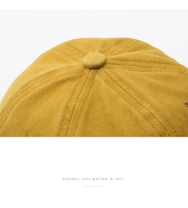 Close-up of mustard yellow cotton baseball cap showing top button and twill stitching