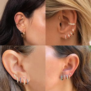 Close-up of gold-plated silver earrings set with pearls and colorful zircons on ear