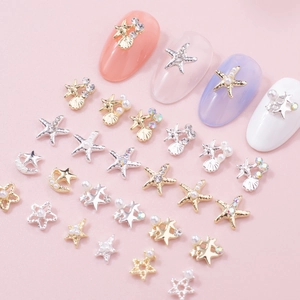 Starfish and seashell nail charms with pearls and rhinestones on pink background