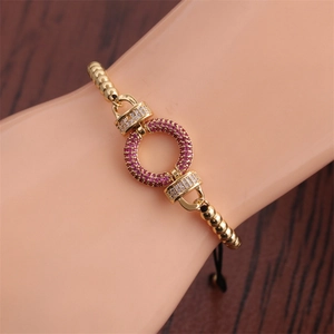 Detail of adjustable gold bead bracelet with purple zircon pendant and horseshoe accents